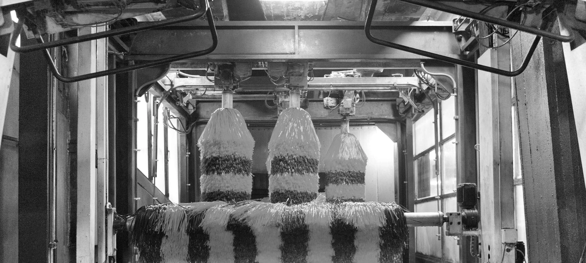 Automated car wash interior featuring three large rotating brushes